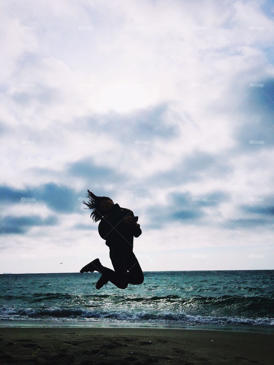 Silhouette of young woman or girl jumping on the beach 