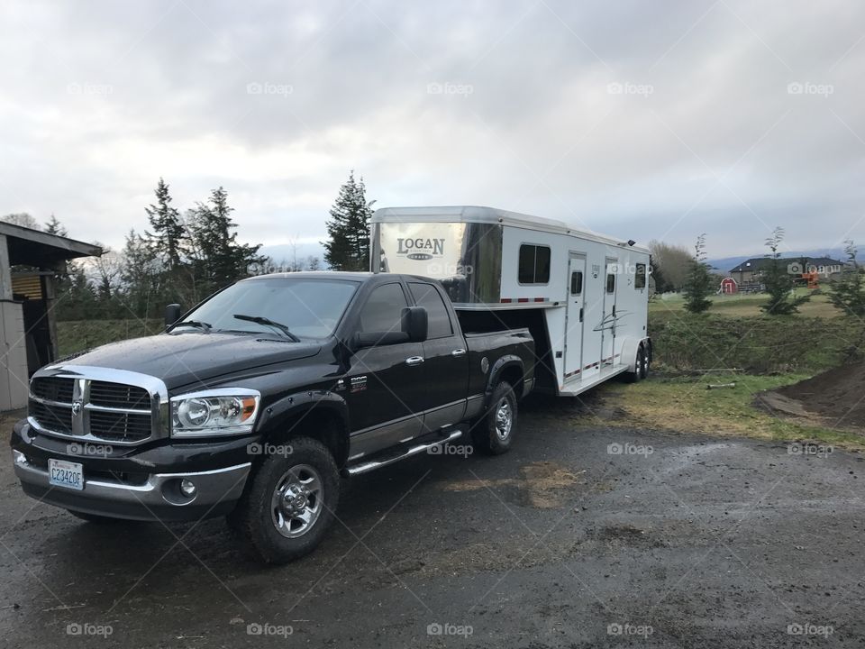 Black Dodge Ram pulling white Logan coach gooseneck horse trailer 