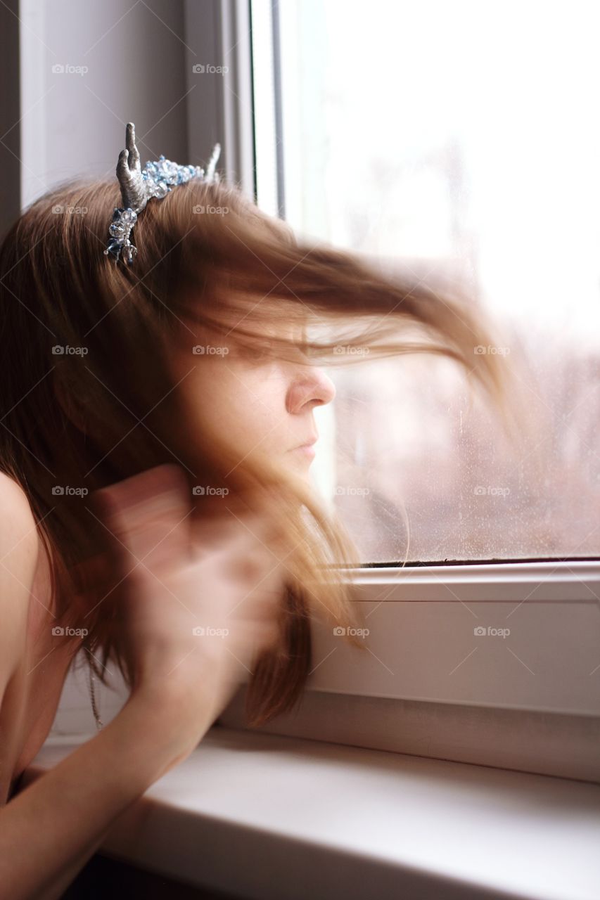 The girl at the window tosses her hair