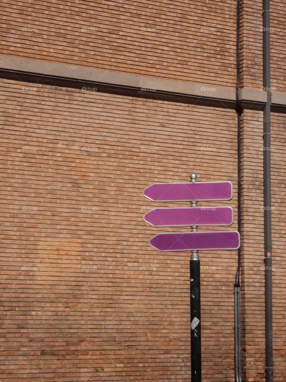 Pink street arrow signs on brick wall background