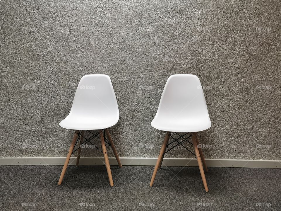White chairs against a grey background.