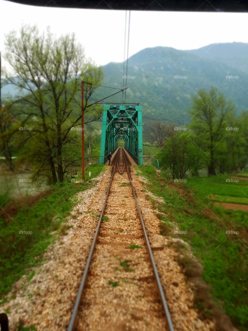 A view from the window of the last passenger wagon to the railway green bridge on the river of Bosna.