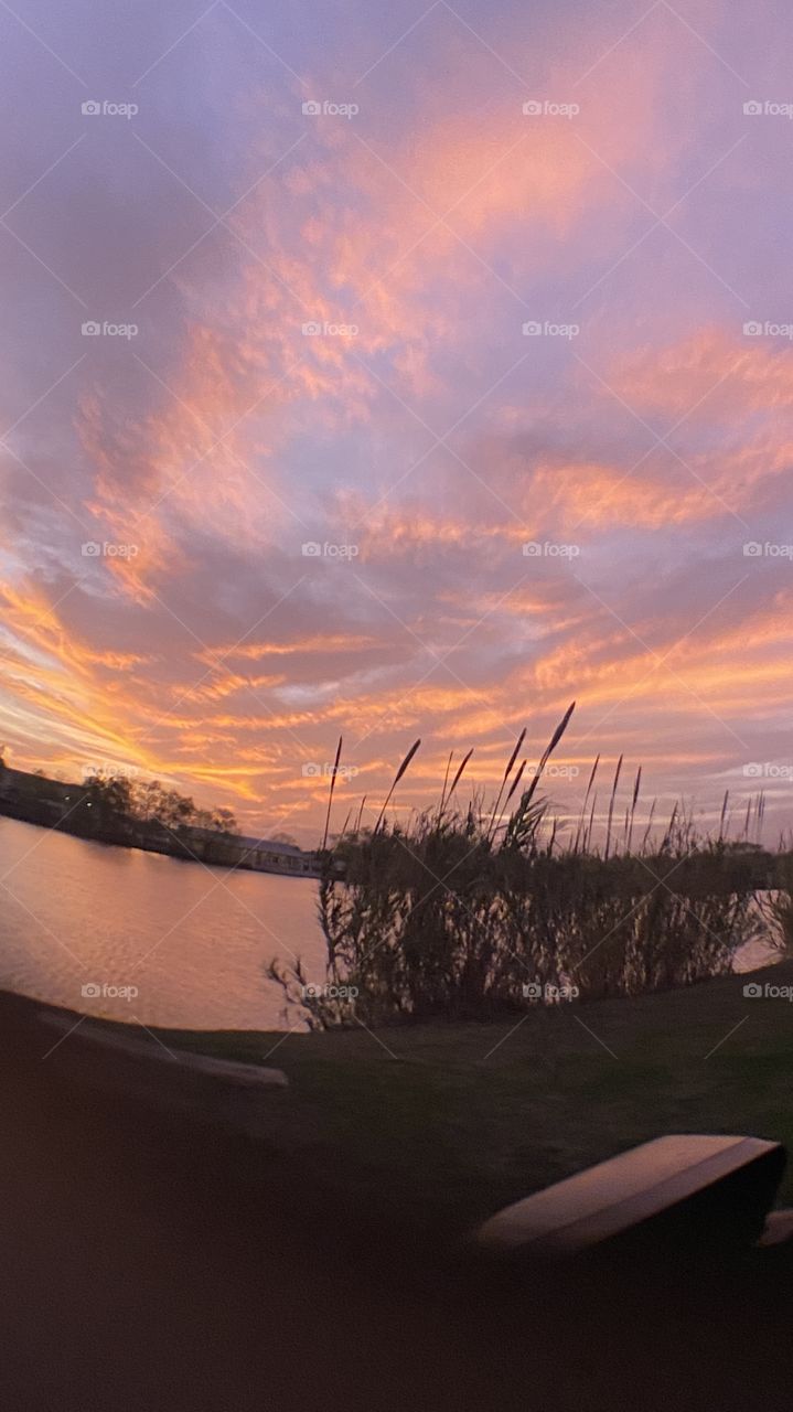 Sundown Completed Sky is opening up. Blistering Orange Slivers along with Yellows upper atmosphere bleeding down to the lower with Grays Blues Violets tops of high clouds getting into the act by opening up.