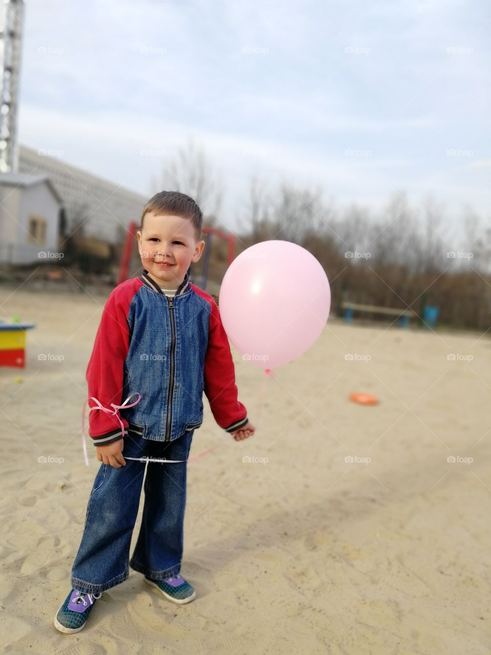 Boy is smilling and holding the pink  balloon
