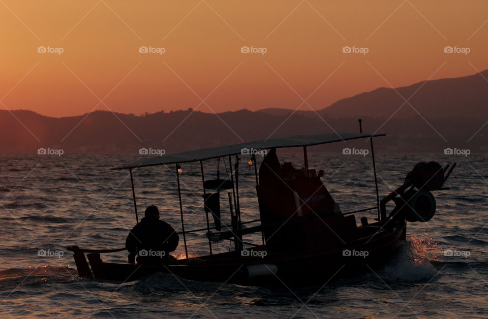 fisher boat with fisherman  fishing at sunset