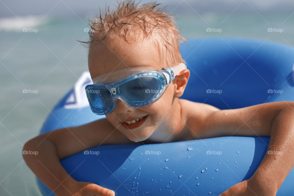 Cute smiling little boy in a blue swim glasses