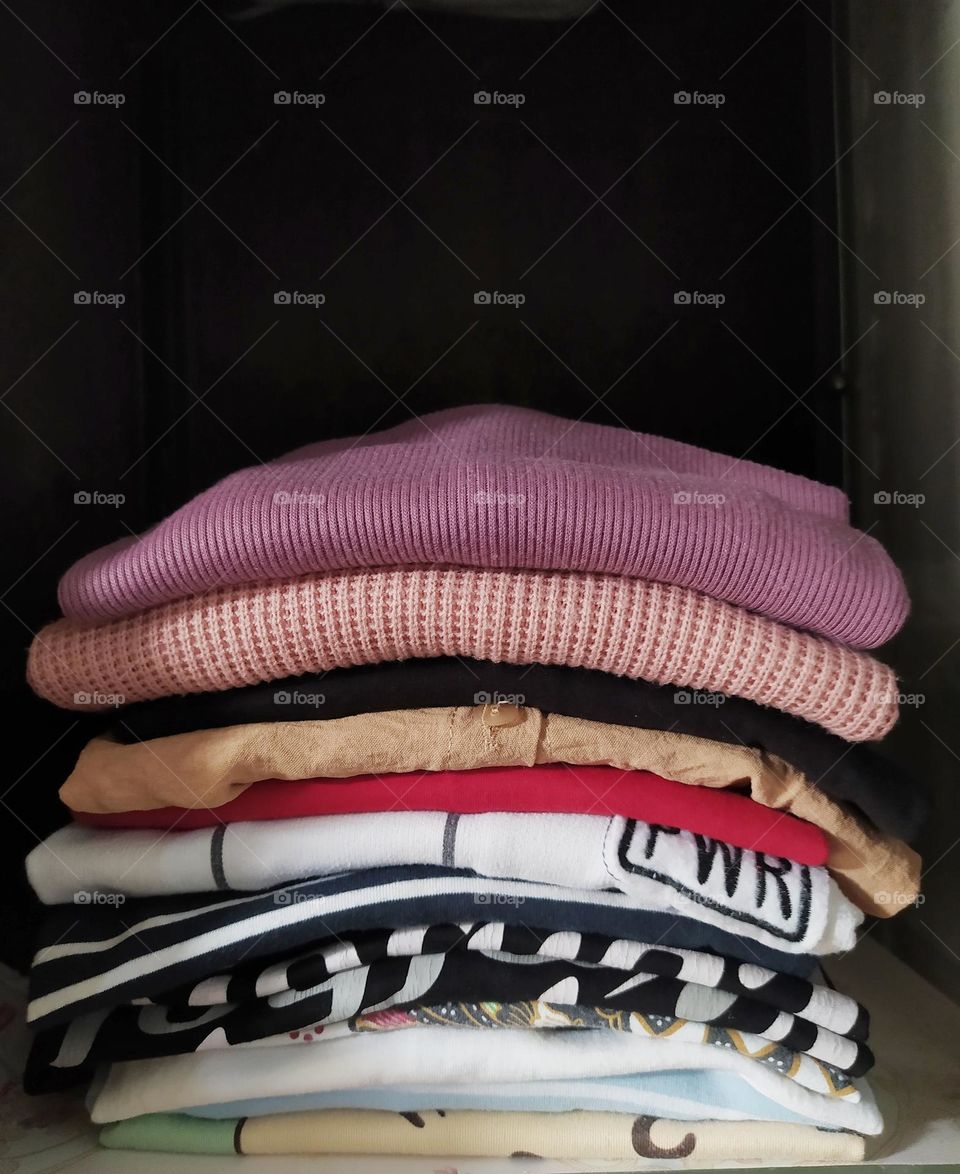 Pile of colored clothes in the closet on a dark background