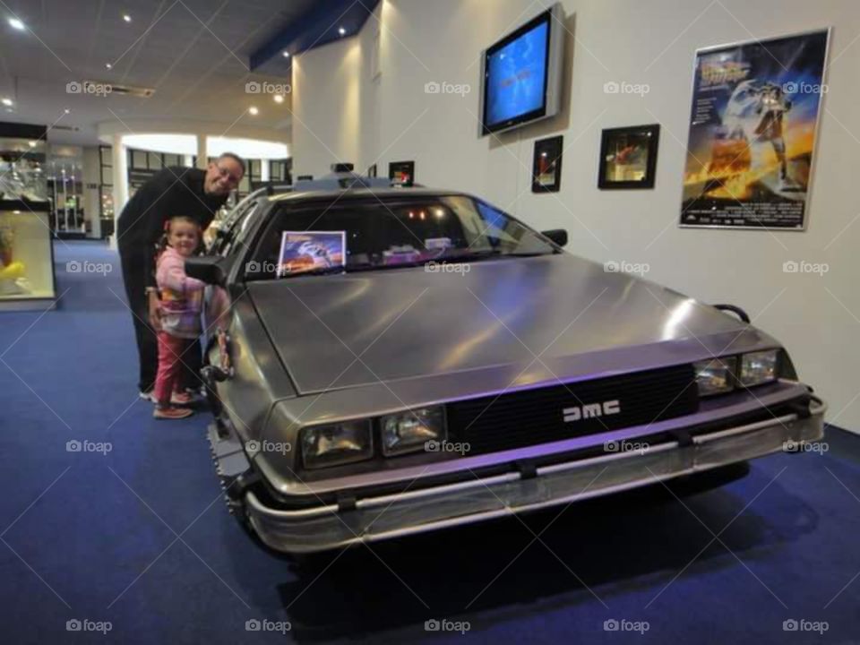 DeLorean car and tourists posing. from the 1980s  movie back to the future