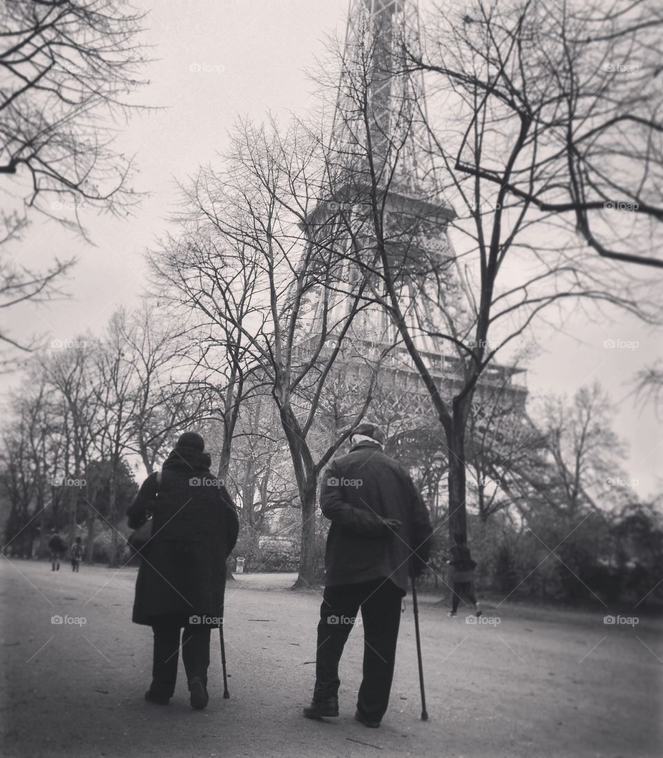 Never Too Old for Romance. An elderly couple takes their daily walk together in front of the Eiffel Tower. -City of Lovers, Paris, France