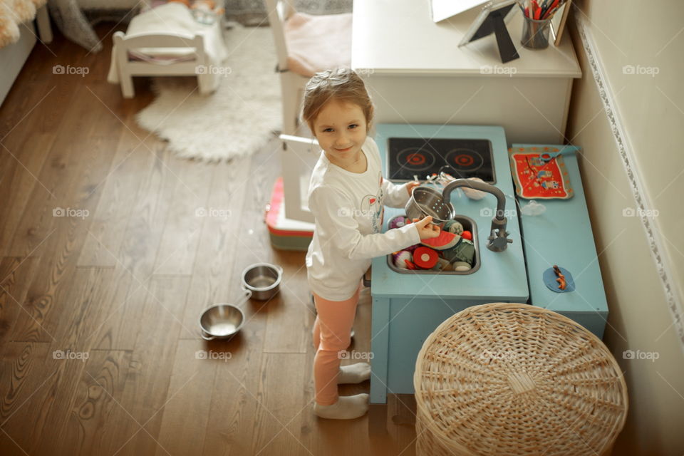 Little girl playing with Ikea kitchen in playroom 