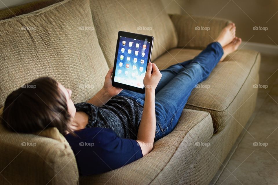 Women with iPad on couch. Female girl with iPad lounging on a couch