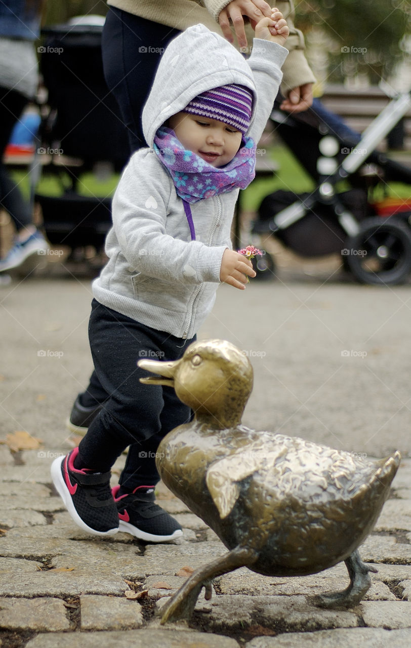 Baby girl playing with ducks statues at Boston's Public Garden
