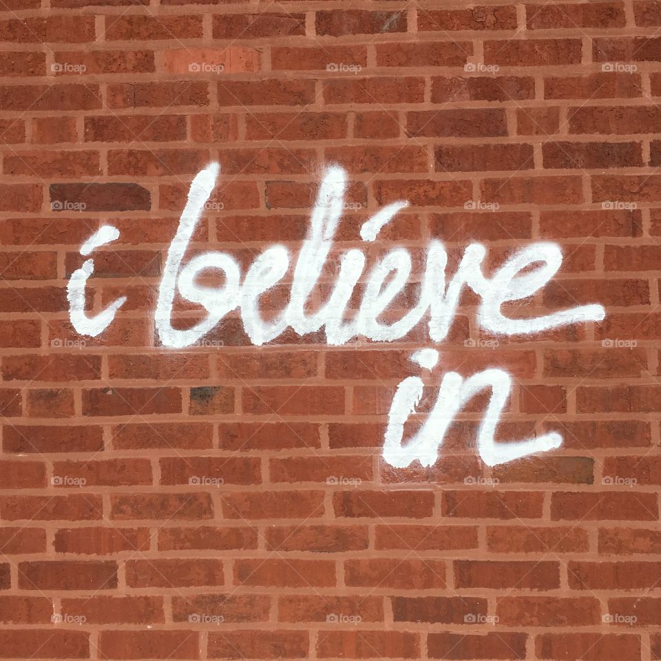 “I believe in” wall art on a red brick wall 