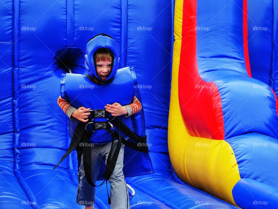 Boy in safety gear exercising in bounce house