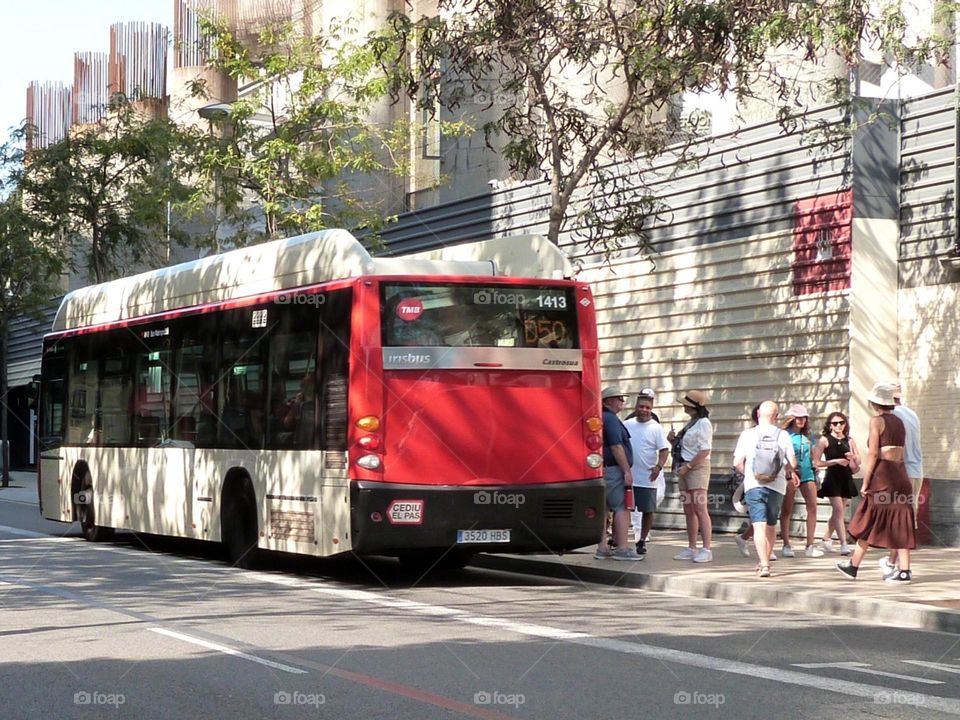 Passengers get off, others get on a bus stopped on a street in Barcelona