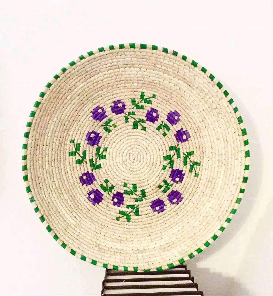 The image shows a group of hand -made dishes of wicker, decorated with colored embroideries with beautiful floral shapes, and is elegantly displayed in a warm corner that combines heritage and beauty, which gives the place an artistic spirit and attr
