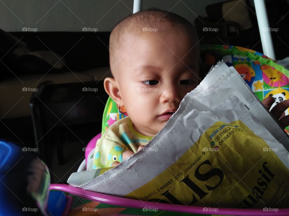 Indonesian baby reading a newspaper