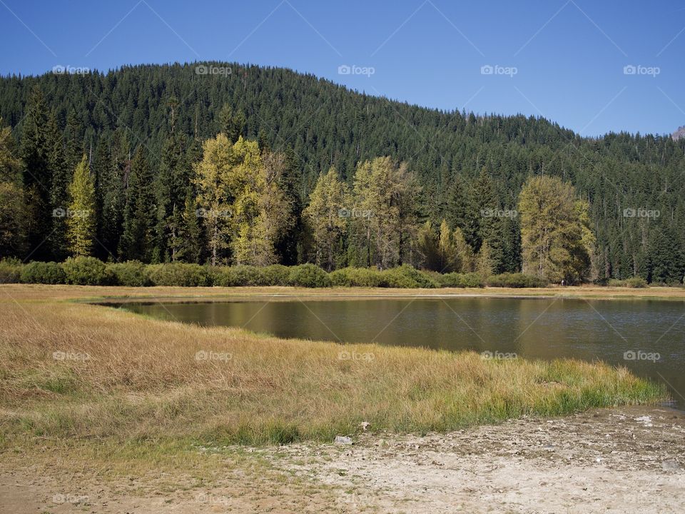 Lost Lake off of the Santiam Pass in Oregon’s mountains with multicolored trees reflecting in its waters on a beautiful sunny fall day.