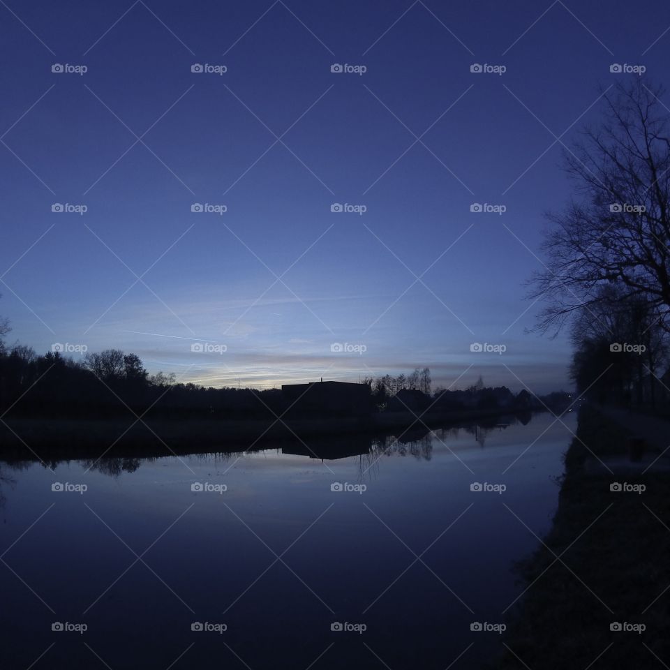 Countryside sunrise showing the colorful sky reflected in the water of the river 