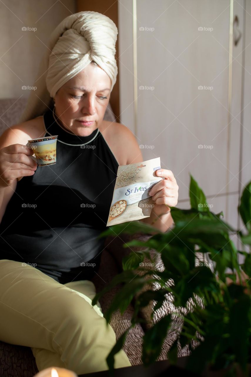 Aged woman with a cosmetics product in her hands, face mask brand St. Ives. Personal care