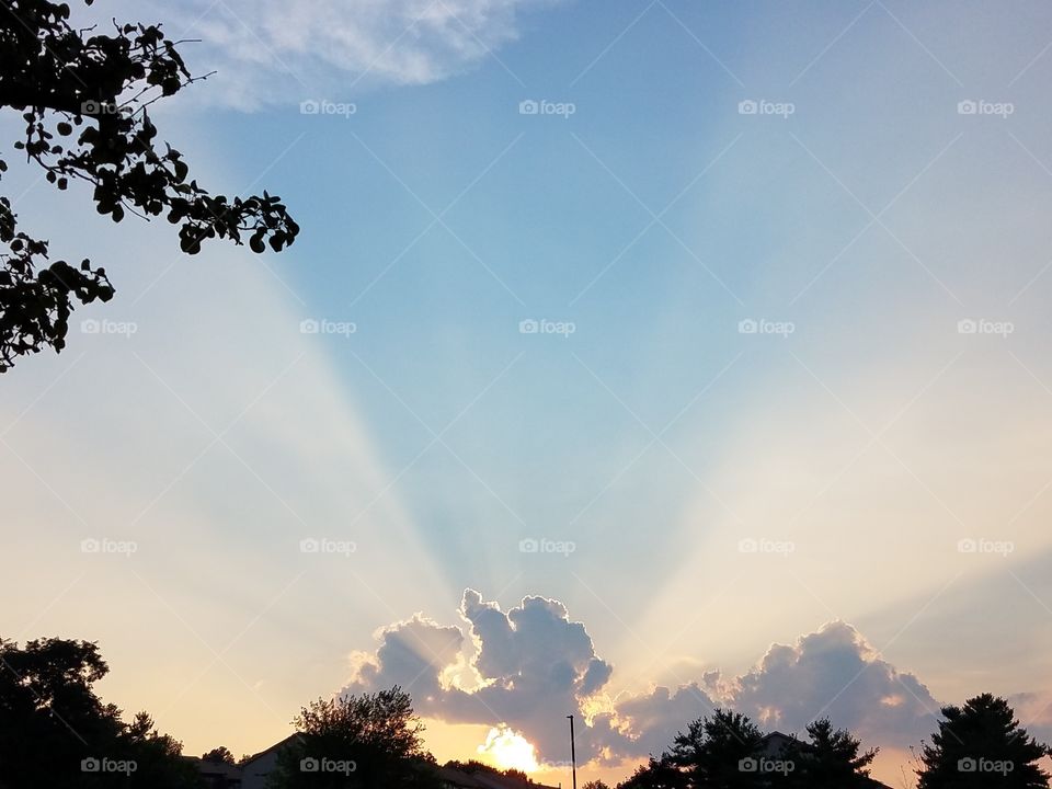 Beaming sun rays pierce through the clouds and form a perfect funnel in the sky.