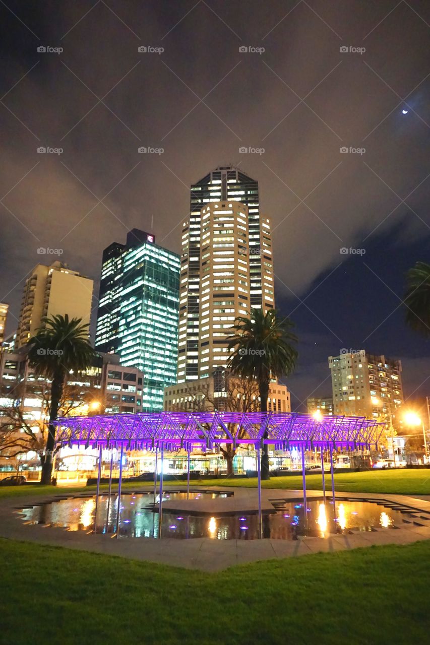 Illuminated skyscrapers in city against sky