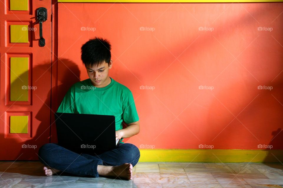 young asian teen with a laptop computer in a living room