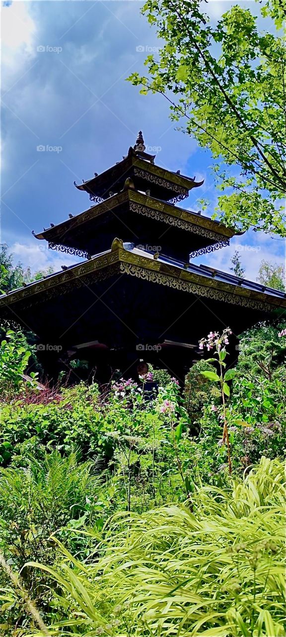 This is a pagoda like structure in “Himalaya Nepal Park” in “Wiesent”, “Bavaria”, Germany set against a sun lit garden with all sorts of lush green vegetation. 2024. Hypnotic Productions