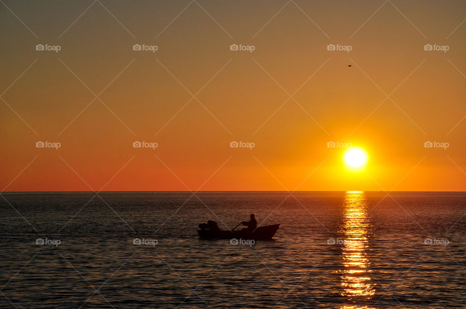 The boat with the fishermen in the sea at sunset