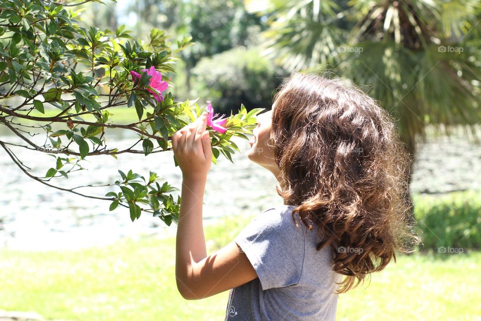Child smelling a flower in the park