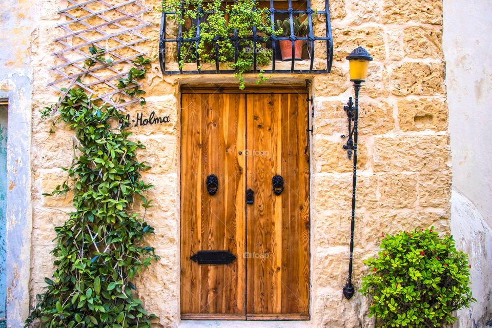 A typical Maltese doorway. Rustic door with a stone cut facade and a lantern. Situated in the village of Rabat, Malta.