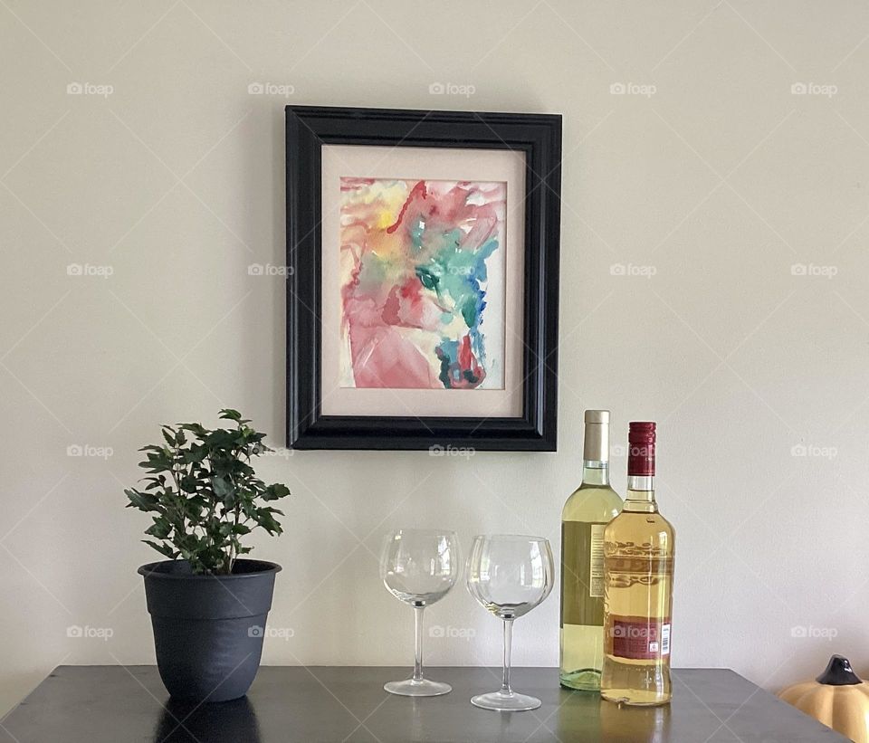 Bella acuarela enmarcada en la pared dos copas y un buen vino para acompañar la velada