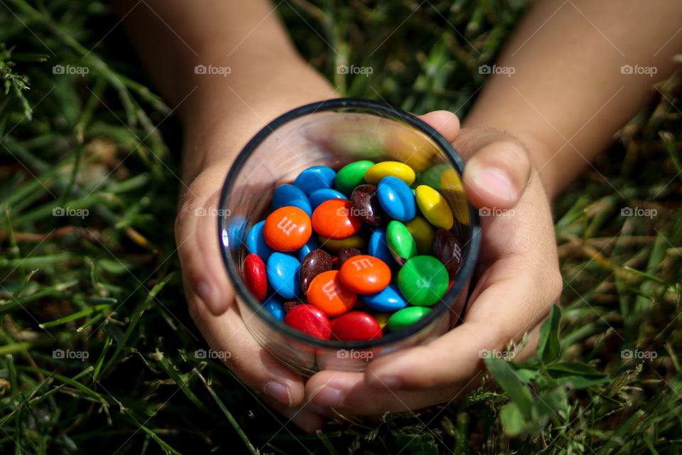 Kid is holding glass with M&Ms