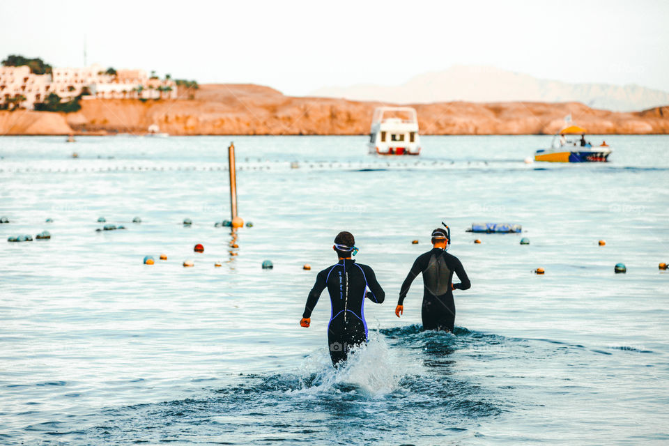 Two scuba divers are going to dive into the sea 