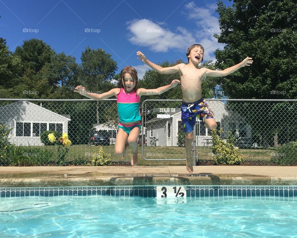 Two kids jumping over the swimming pool