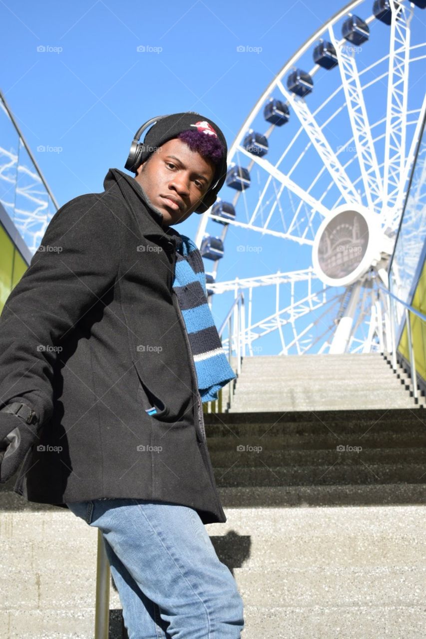 Leaning on the rail of a stairway at Navy Pier in Chicago, ferris wheel in background. 