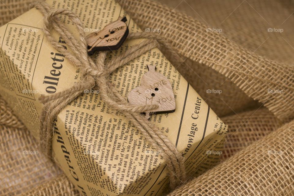 close up gift box with hearts and space for text on sackcloth background.