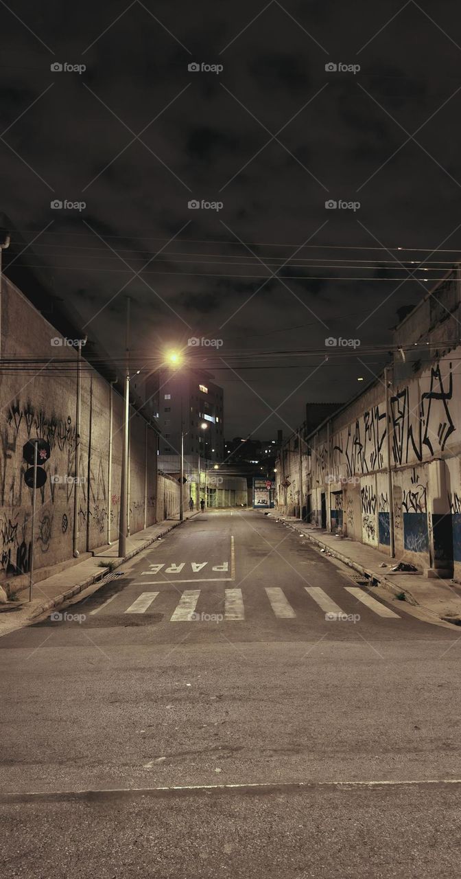 Empty streets under the warm glow of streetlights, where urban silence takes over the night.