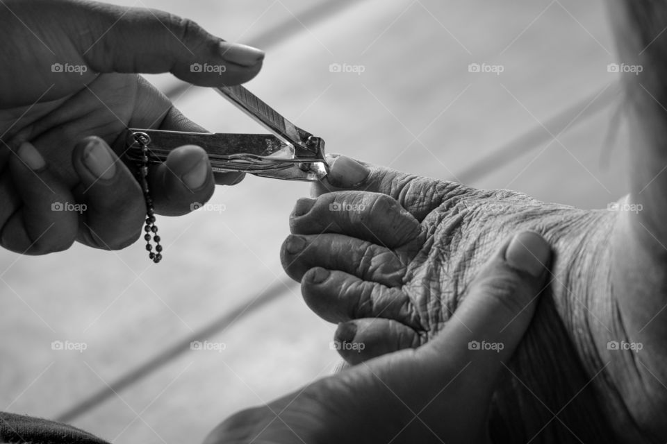 Granddaughter is cutting nails for Grandma.