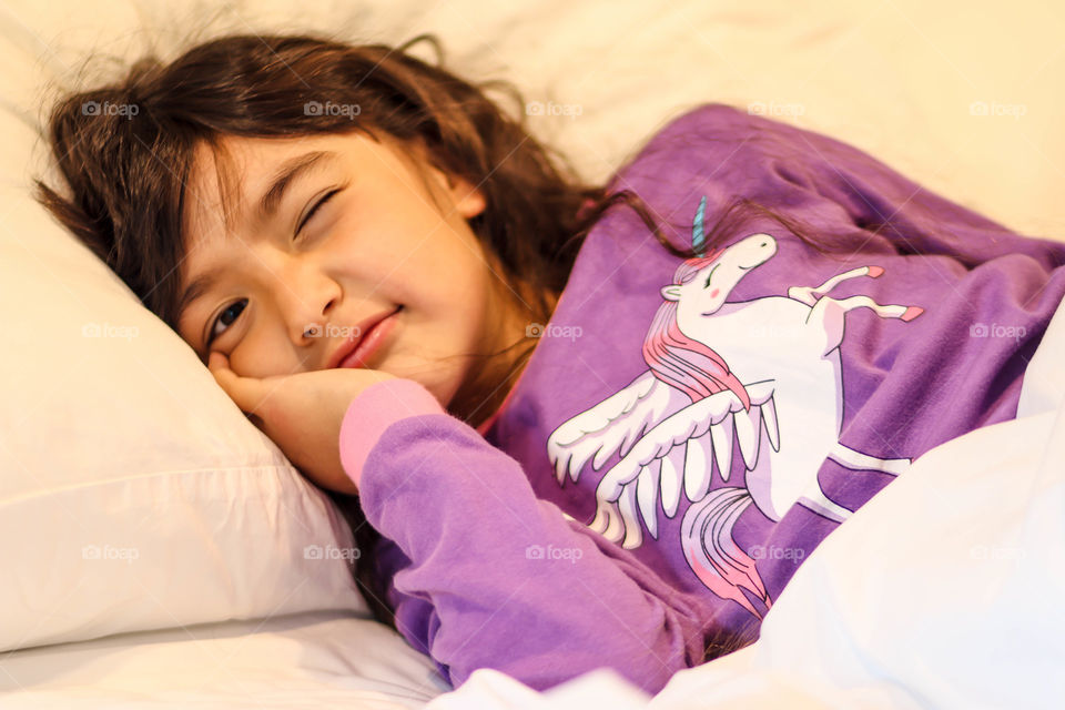 Cute little girl in pajamas witn unicorns and rainbows