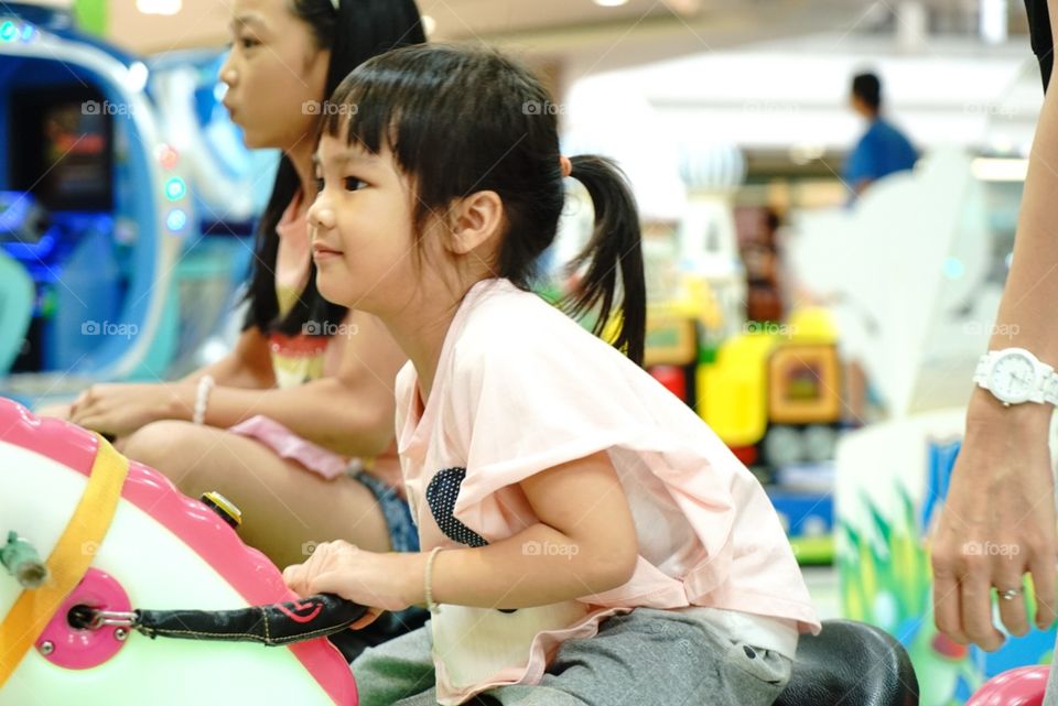 Asian girls riding on game arcade ride 