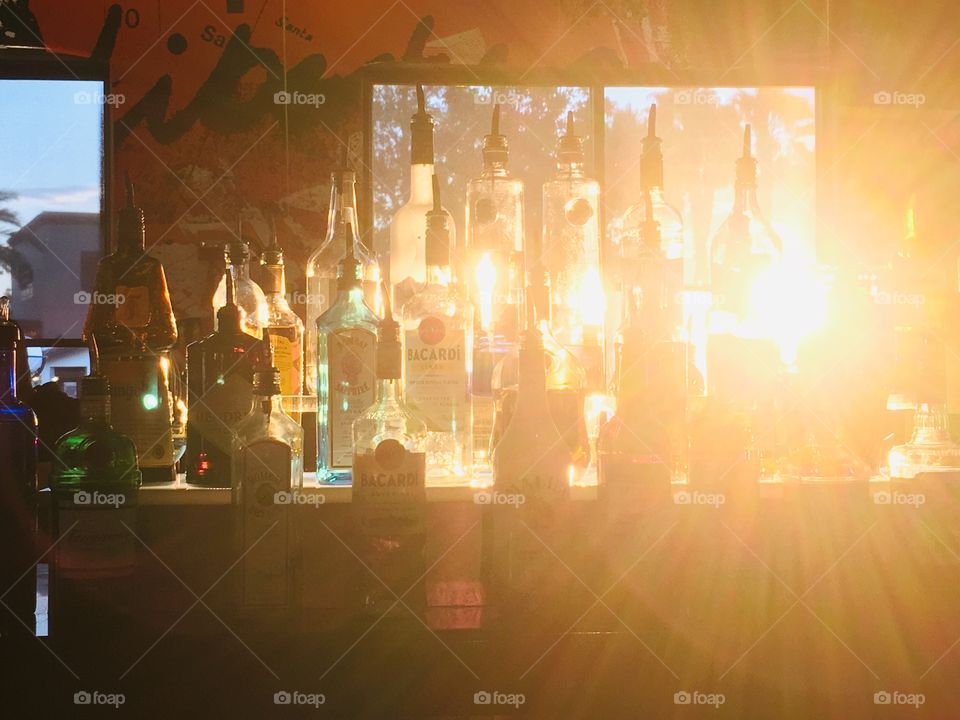 Sunshine shining through liquor bottles at the bar