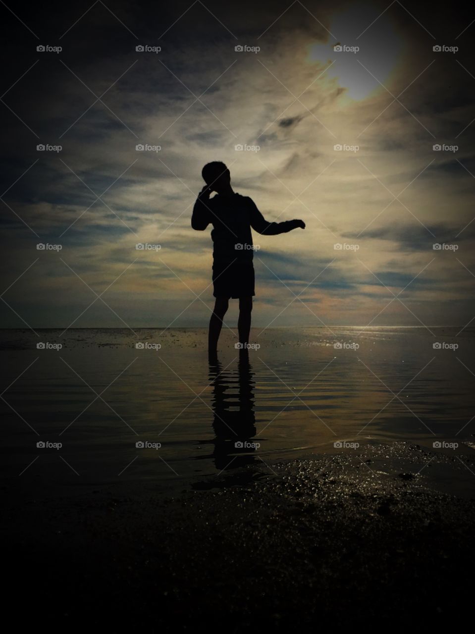 Silhouette of boy on beach at sunrise 
