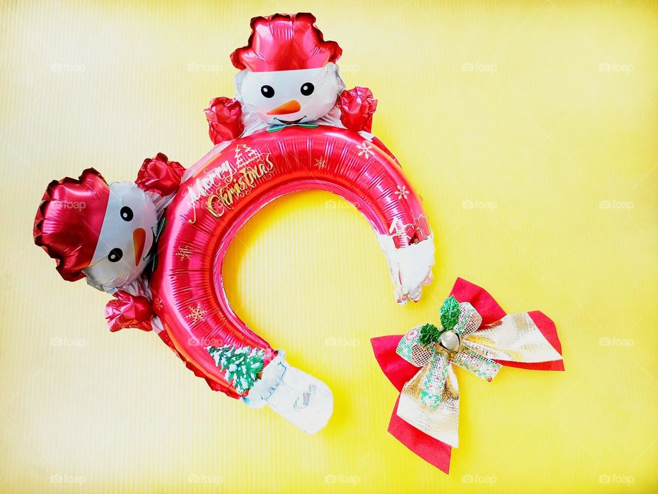 Snowman Christmas headband and Christmas bow on yellow background horizontal composition.