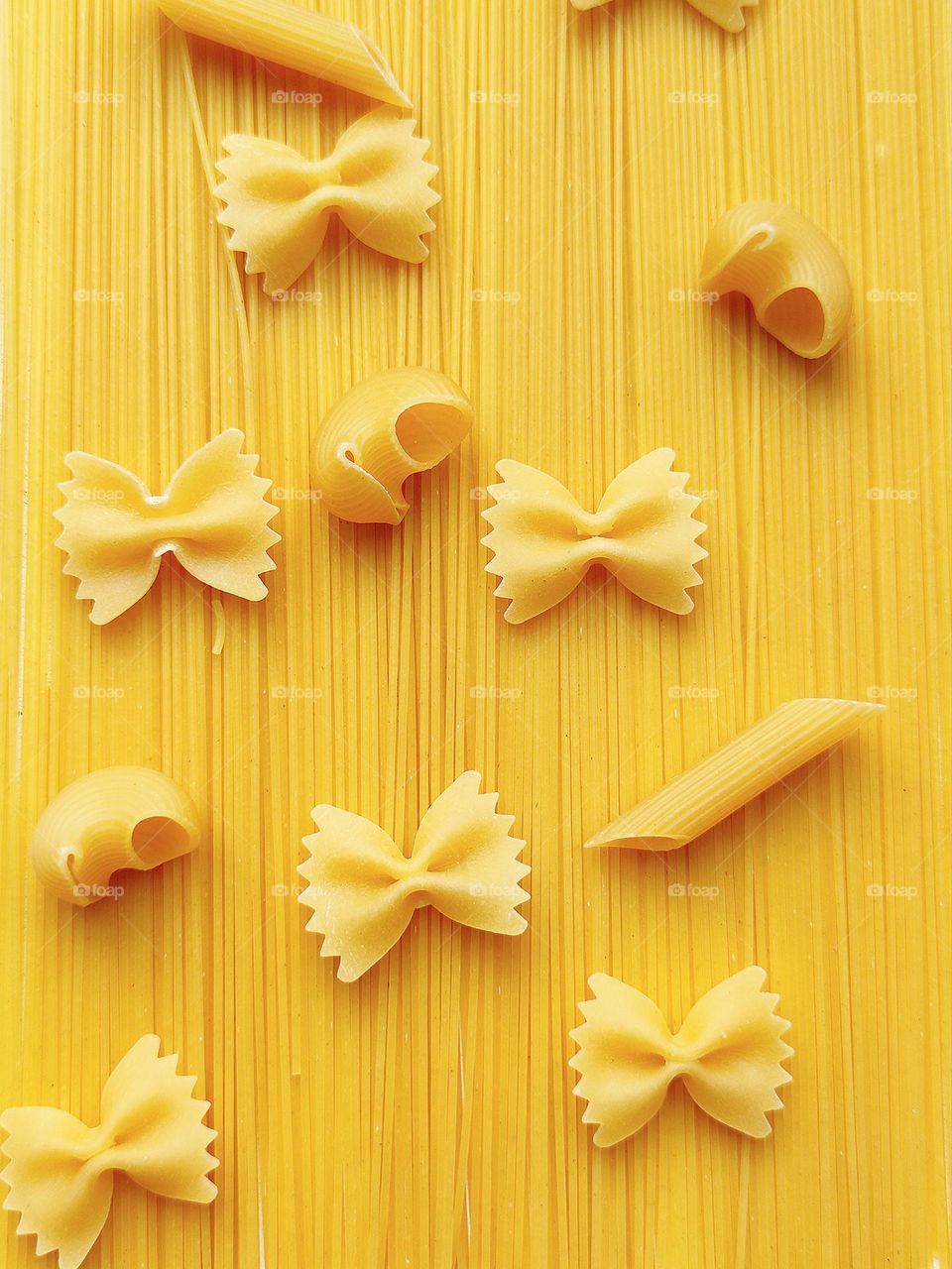 Yellow. Fantasy with different shapes of pasta. On long spaghetti are pasta "Farfalle" in the shape of a butterfly, horns "Pipe Righte" and "Rigatonni" in the form of tubes