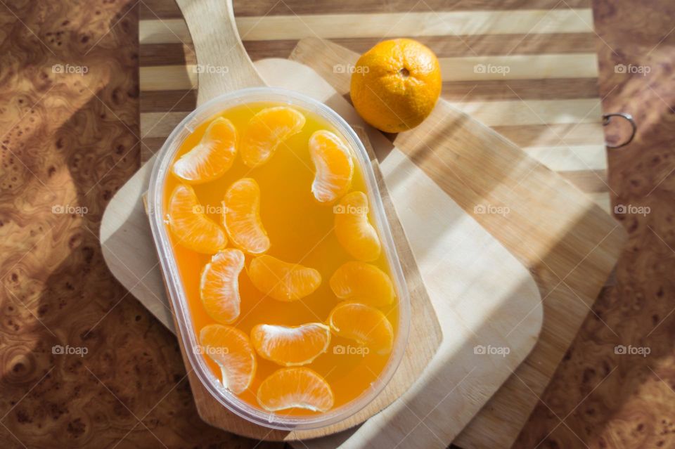 Delicious orange jelly with tangerine slices in a container and jelly worms.