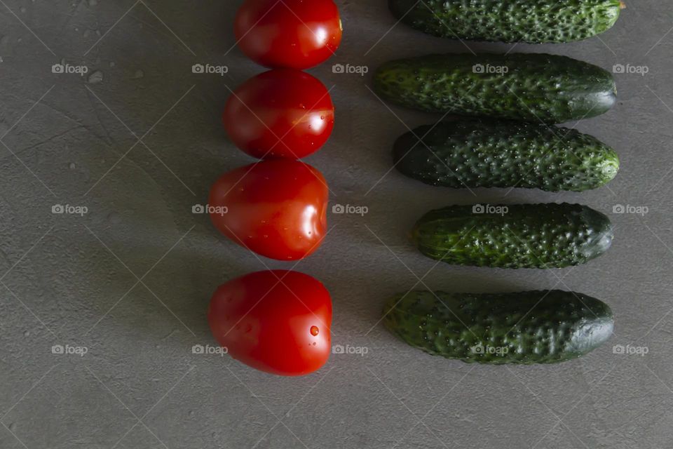 Fresh, bright, juicy vegetables and herbs for preparing salads and other vegetable dishes are on a gray, kitchen worktop.