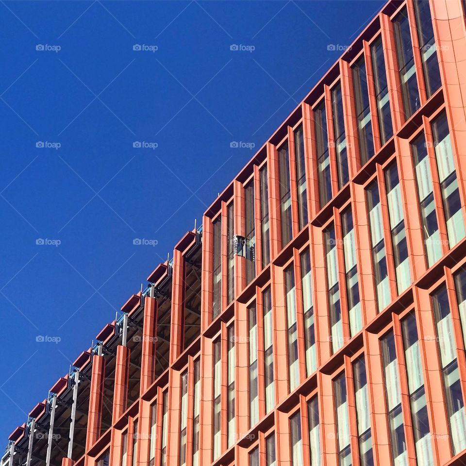 Manchester Architecture, taken against a bright and clear blue sky. The orange building pops out in colourful bursts
