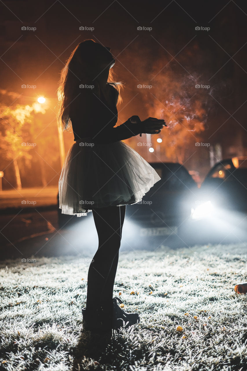 woman wearing ballet tutu in the car lights at night