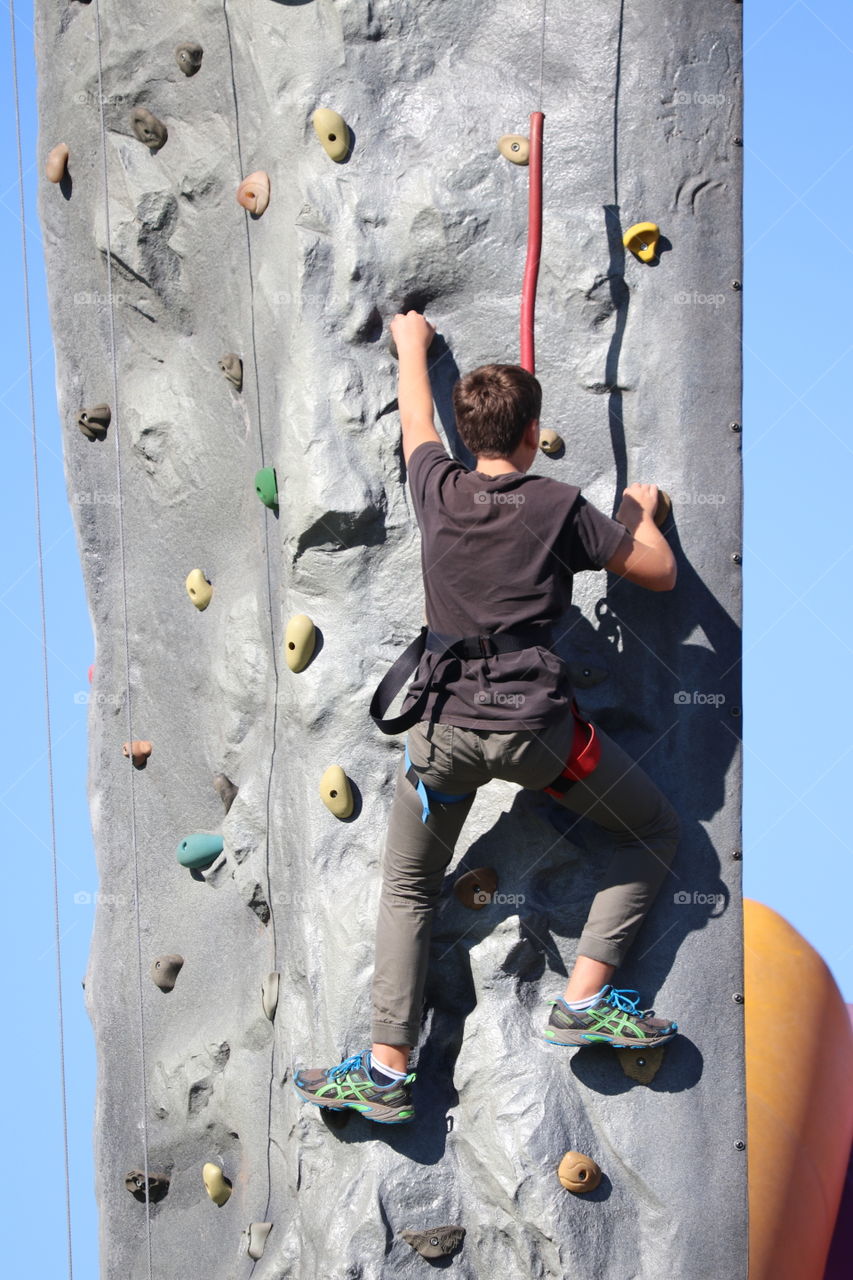 Twelve year old boy rock climbing outdoors